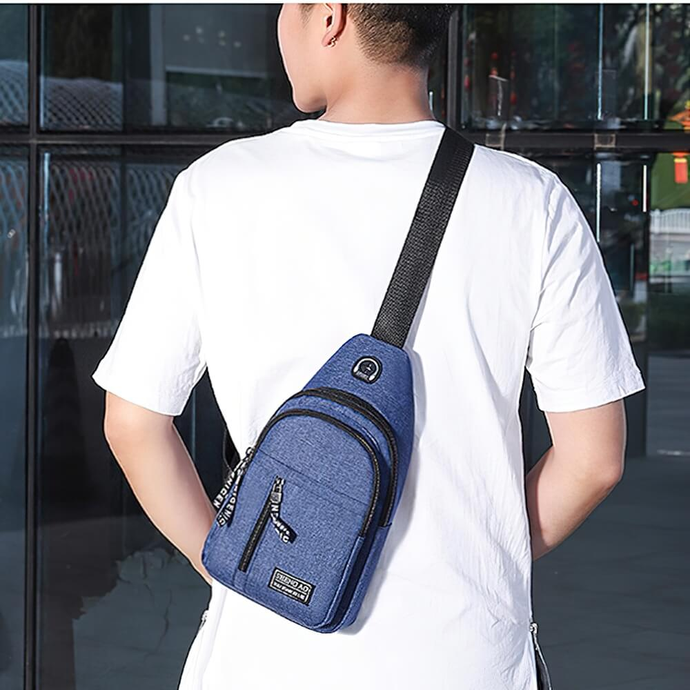 Man wearing a small waterproof single shoulder strap bag in blue, ideal for the modern man on the go.